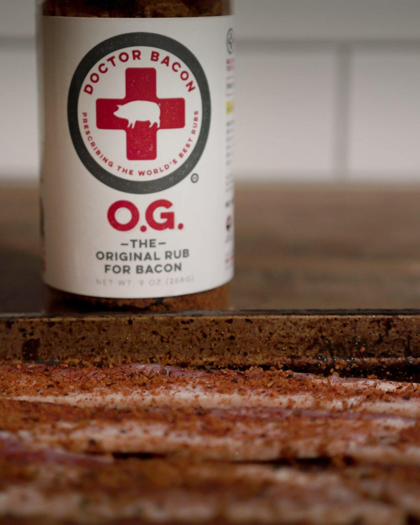 Bottle of Dr, Bacon O.G. Spice Rub in front of a tray of seasoned bacon.